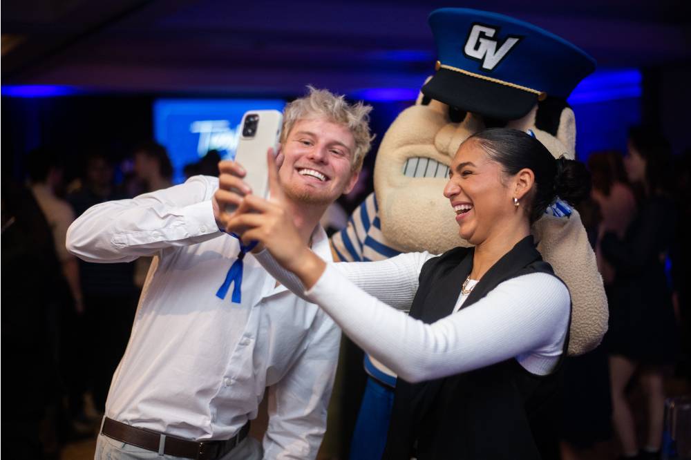 Two students taking a selfie with Louie the Laker.